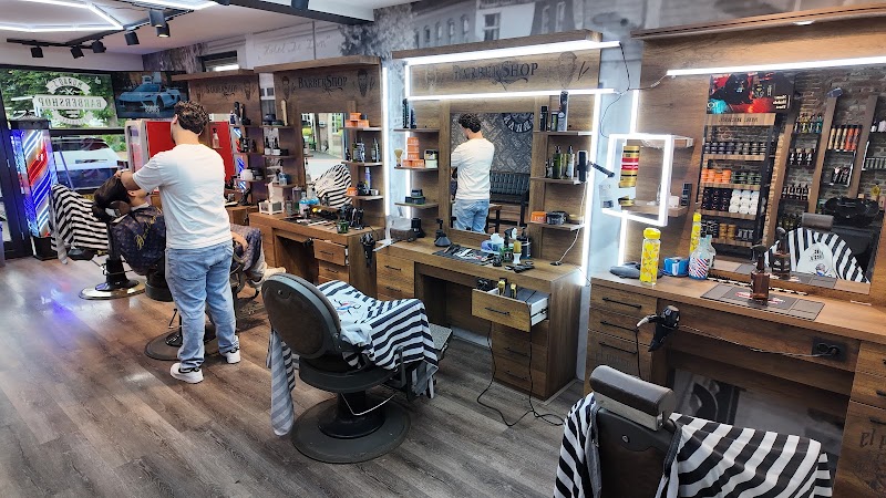 De stations in de barbershop met verlichte spiegels, houten kasten en gestreepte kapmantels.